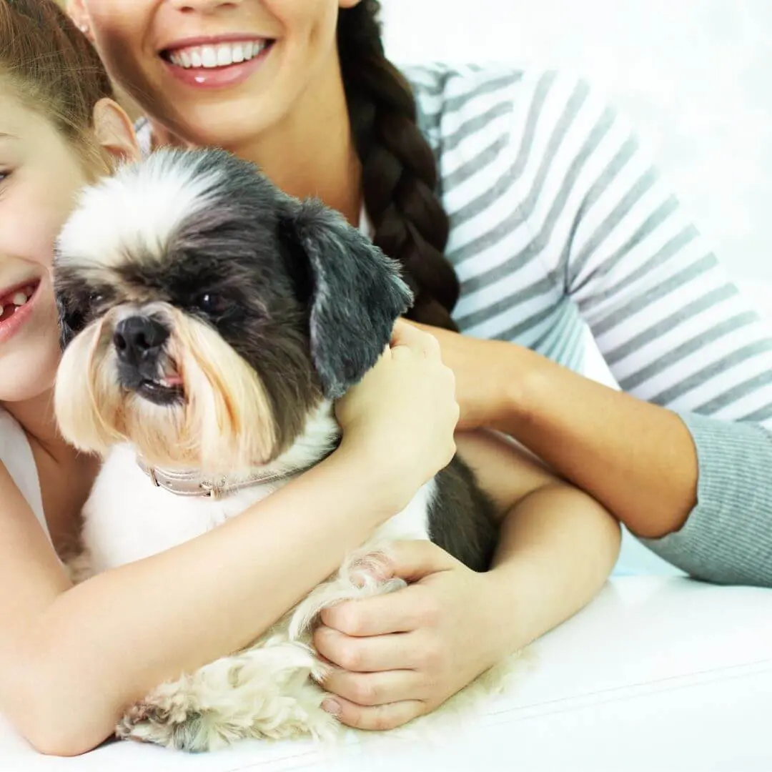 A woman and a girl happily holding a dog